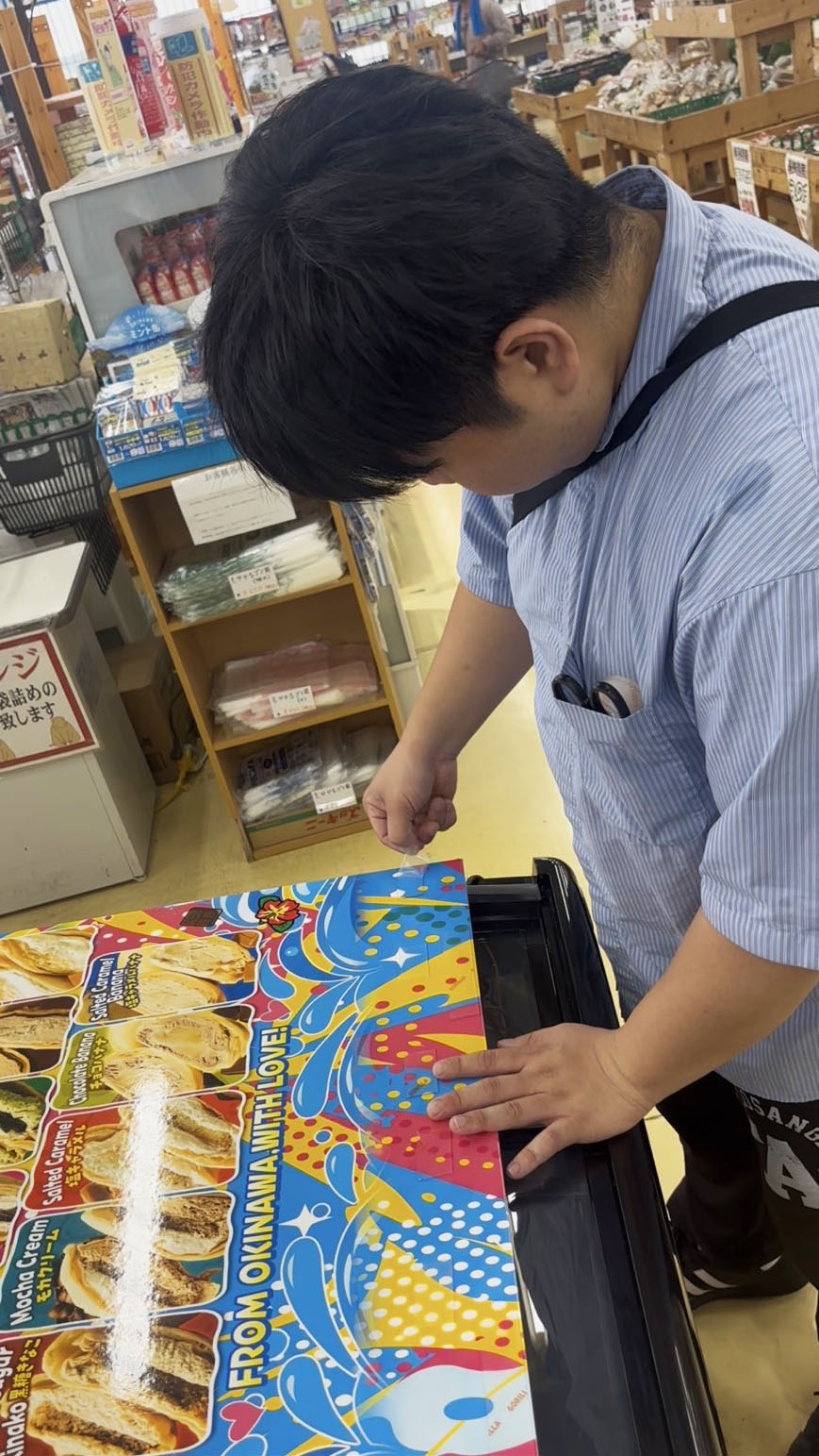 おくるみクレープの販売用冷凍庫に案内パネルを取り付けている様子